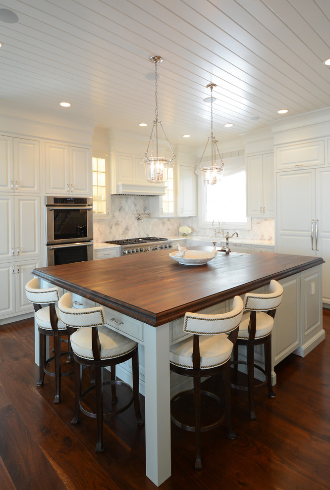 Large transitional dark wood floor eat-in kitchen photo in Atlanta with a farmhouse sink, raised-panel cabinets, white cabinets, marble countertops, white backsplash, stone tile backsplash, stainless steel appliances and two islands