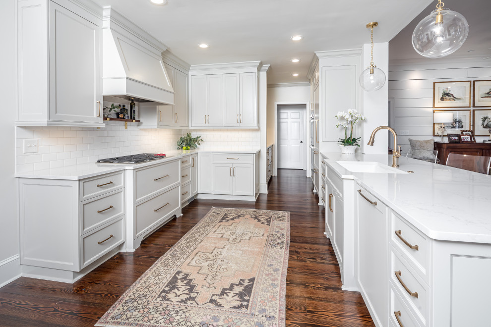 Inspiration for a transitional u-shaped medium tone wood floor and brown floor kitchen remodel in Other with an undermount sink, gray cabinets, white backsplash, subway tile backsplash, paneled appliances, a peninsula, white countertops and recessed-panel cabinets