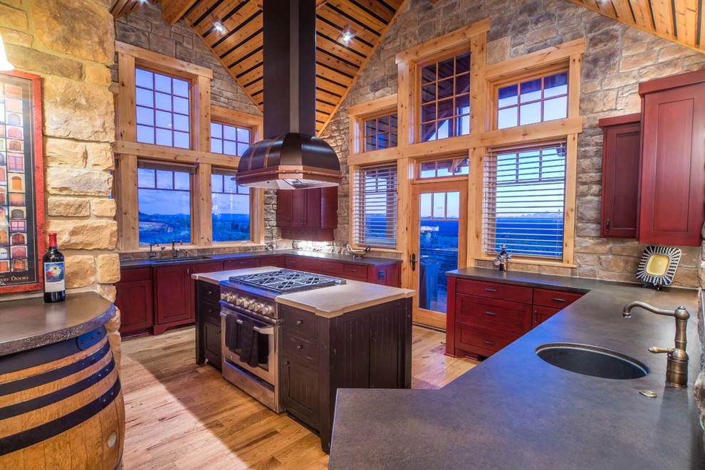 Kitchen - mid-sized rustic u-shaped medium tone wood floor and brown floor kitchen idea in Other with a double-bowl sink, shaker cabinets, red cabinets, solid surface countertops, brown backsplash, stone tile backsplash, paneled appliances and an island