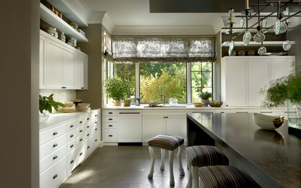 На фото: угловая кухня в стиле неоклассика (современная классика) с врезной мойкой, фасадами с утопленной филенкой, белыми фасадами, белым фартуком, островом и окном
