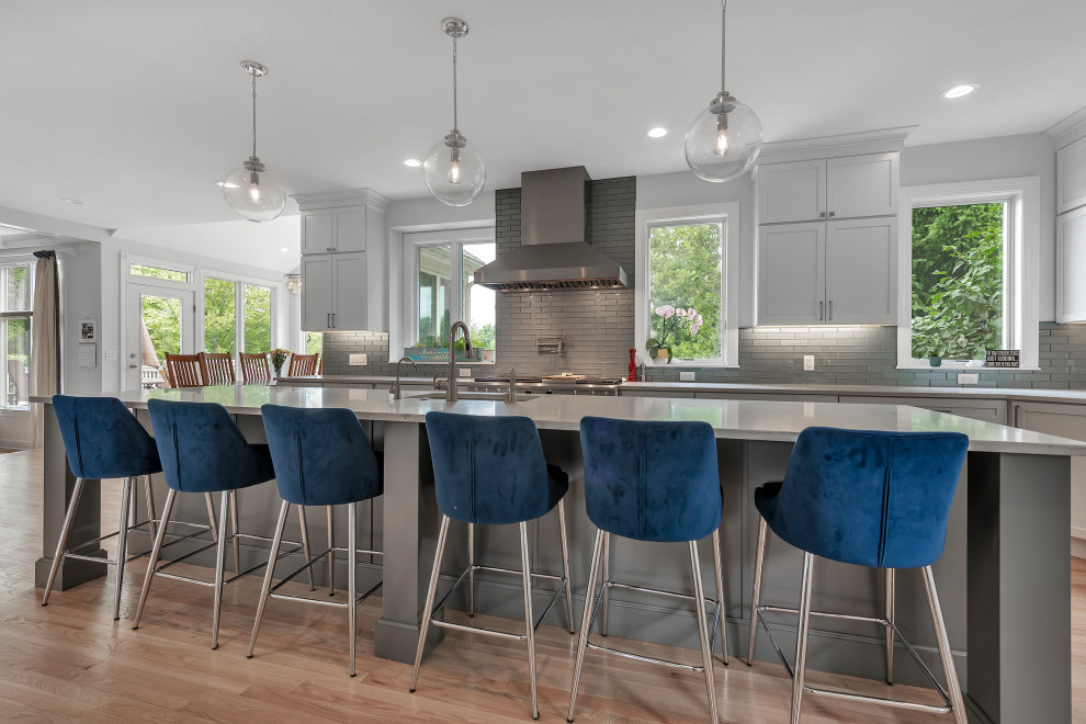Inspiration for a large timeless galley medium tone wood floor and brown floor eat-in kitchen remodel in Detroit with an undermount sink, shaker cabinets, gray cabinets, quartzite countertops, blue backsplash, subway tile backsplash, stainless steel appliances, an island and white countertops