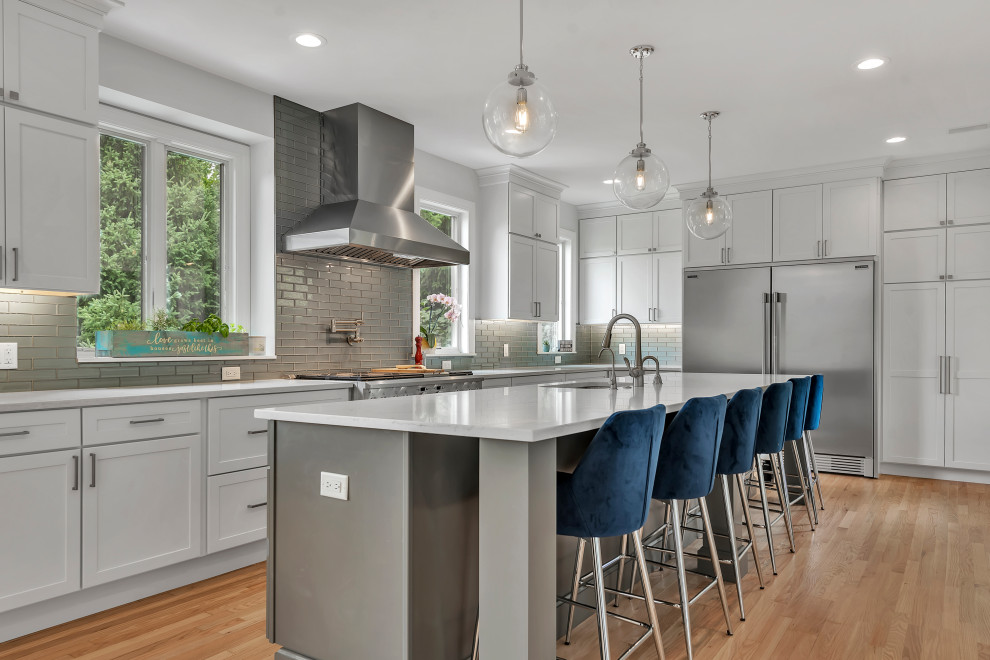 Inspiration for a large transitional galley medium tone wood floor and brown floor eat-in kitchen remodel in Detroit with an undermount sink, shaker cabinets, gray cabinets, quartzite countertops, blue backsplash, subway tile backsplash, stainless steel appliances, an island and white countertops
