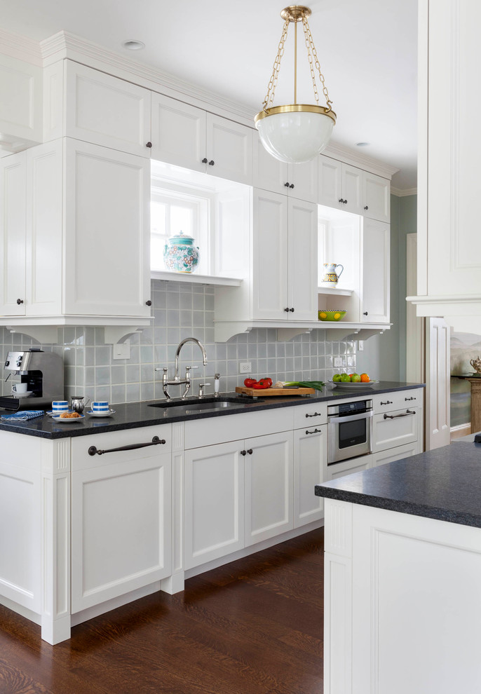 Klassische Küche mit Unterbauwaschbecken, Schrankfronten im Shaker-Stil, weißen Schränken, Küchenrückwand in Blau, Rückwand aus Glasfliesen, Küchengeräten aus Edelstahl und dunklem Holzboden in Boston