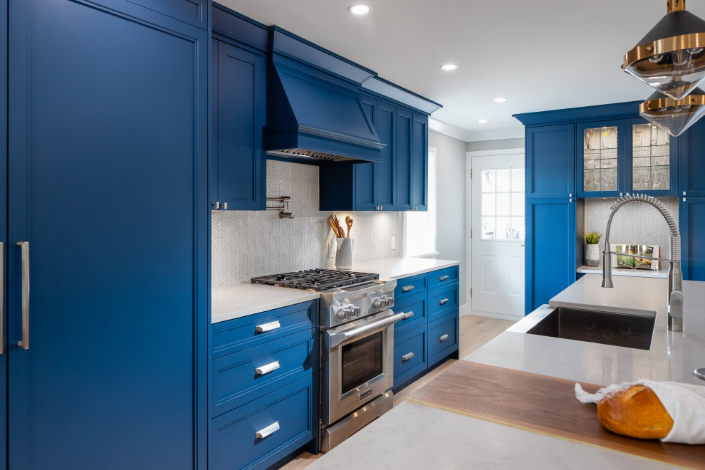 Inspiration for a large transitional galley light wood floor and beige floor open concept kitchen remodel in Vancouver with a farmhouse sink, shaker cabinets, blue cabinets, quartz countertops, white backsplash, mosaic tile backsplash, paneled appliances, an island and gray countertops