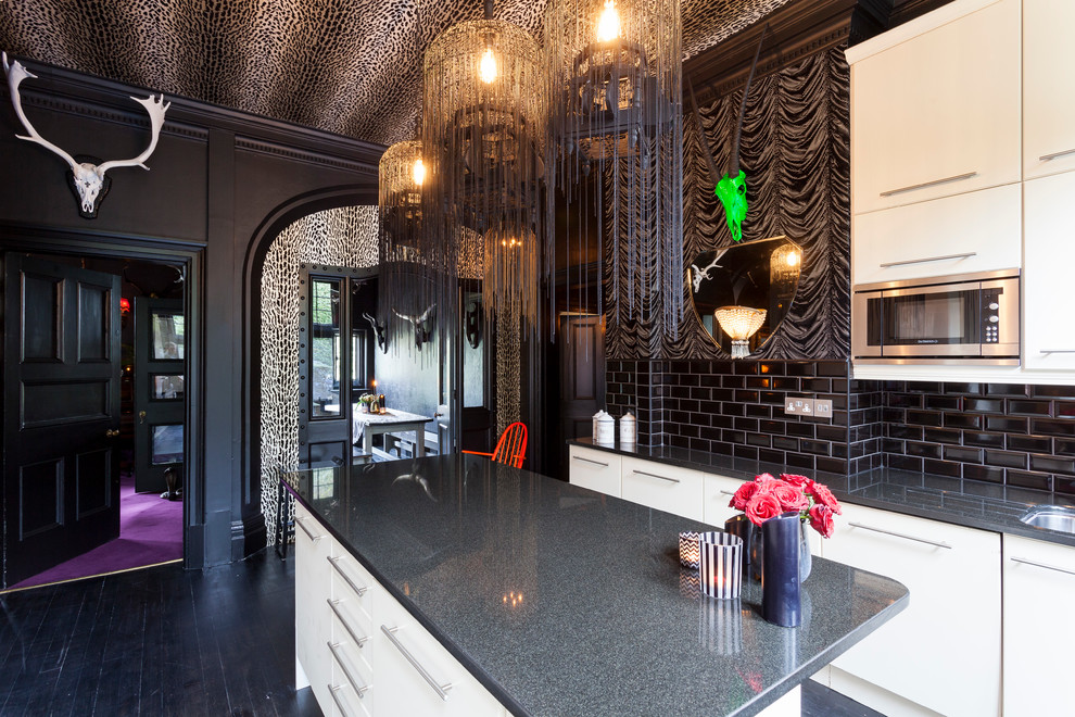 Foto på ett eklektiskt kök, med släta luckor, vita skåp, svart stänkskydd, stänkskydd i tunnelbanekakel, mörkt trägolv och en köksö