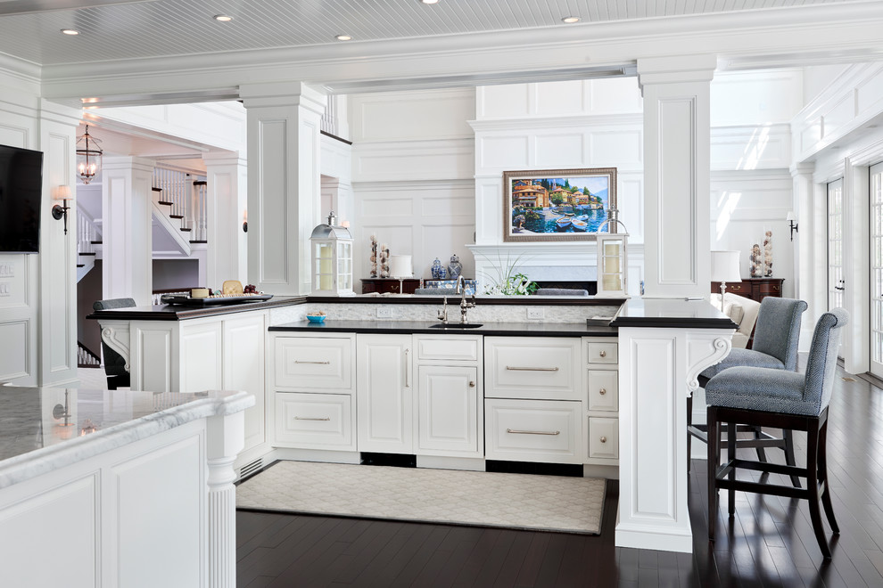 Expansive contemporary single-wall kitchen/diner in Philadelphia with a built-in sink, recessed-panel cabinets, white cabinets, white splashback, ceramic splashback, white appliances, dark hardwood flooring, an island and onyx worktops.