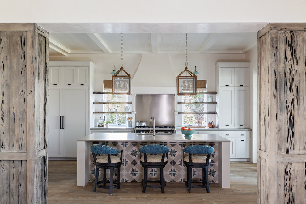 Inspiration for a coastal light wood floor kitchen remodel in Charleston with an undermount sink, shaker cabinets, white cabinets, metallic backsplash, black appliances, an island and gray countertops