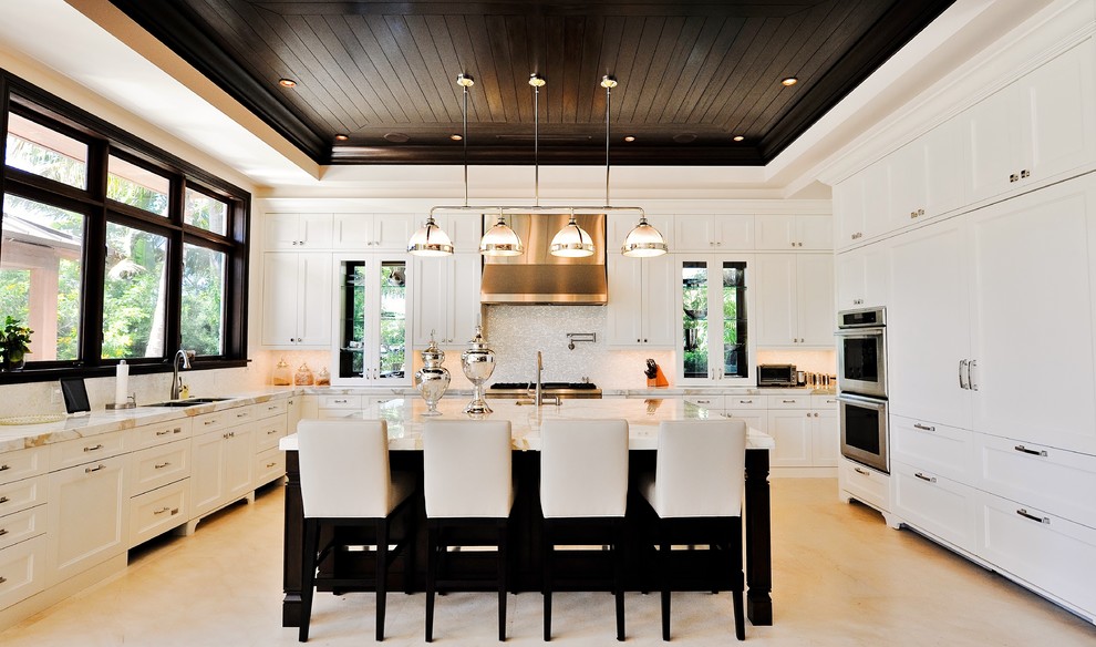 Klassische Küche in U-Form mit Elektrogeräten mit Frontblende, weißen Schränken, Küchenrückwand in Weiß und Schrankfronten mit vertiefter Füllung in Miami