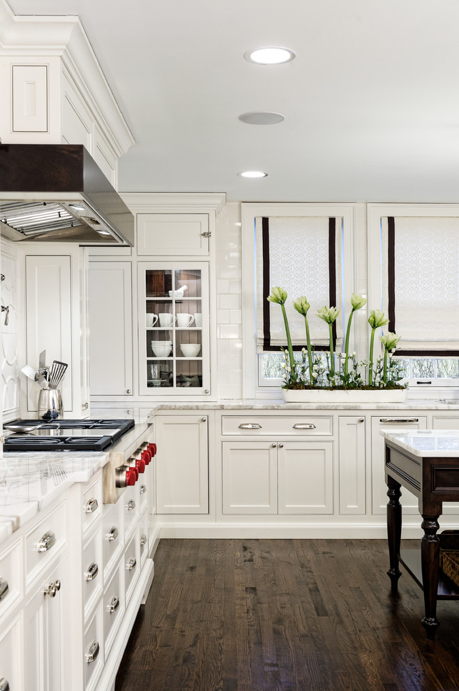 Exempel på ett klassiskt u-kök, med en undermonterad diskho, vita skåp, marmorbänkskiva, vitt stänkskydd, stänkskydd i keramik, integrerade vitvaror och mörkt trägolv