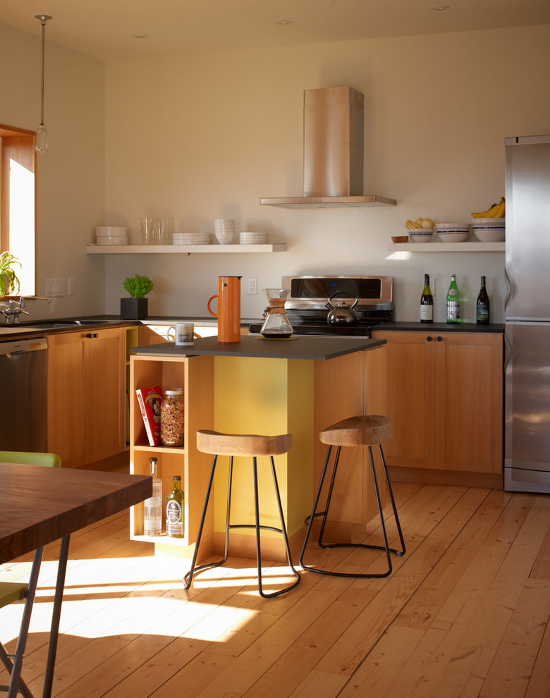 Cette photo montre une cuisine ouverte chic en L et bois brun avec un placard à porte shaker, un électroménager en acier inoxydable, un sol en bois brun et îlot.