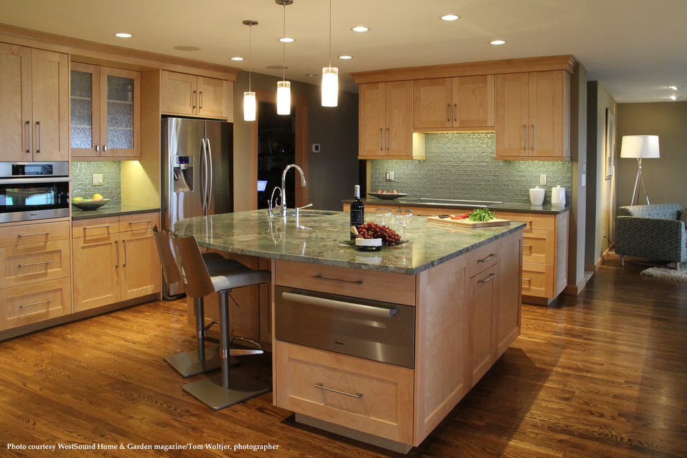 Photo of a large classic u-shaped kitchen/diner in Seattle with a submerged sink, shaker cabinets, light wood cabinets, granite worktops, green splashback, glass tiled splashback, stainless steel appliances, medium hardwood flooring, an island, brown floors and multicoloured worktops.