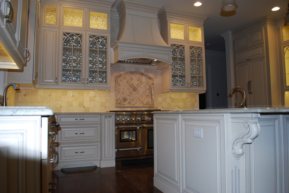Foto på ett mellanstort vintage kök, med en undermonterad diskho, luckor med upphöjd panel, vita skåp, beige stänkskydd, rostfria vitvaror, mörkt trägolv och en köksö