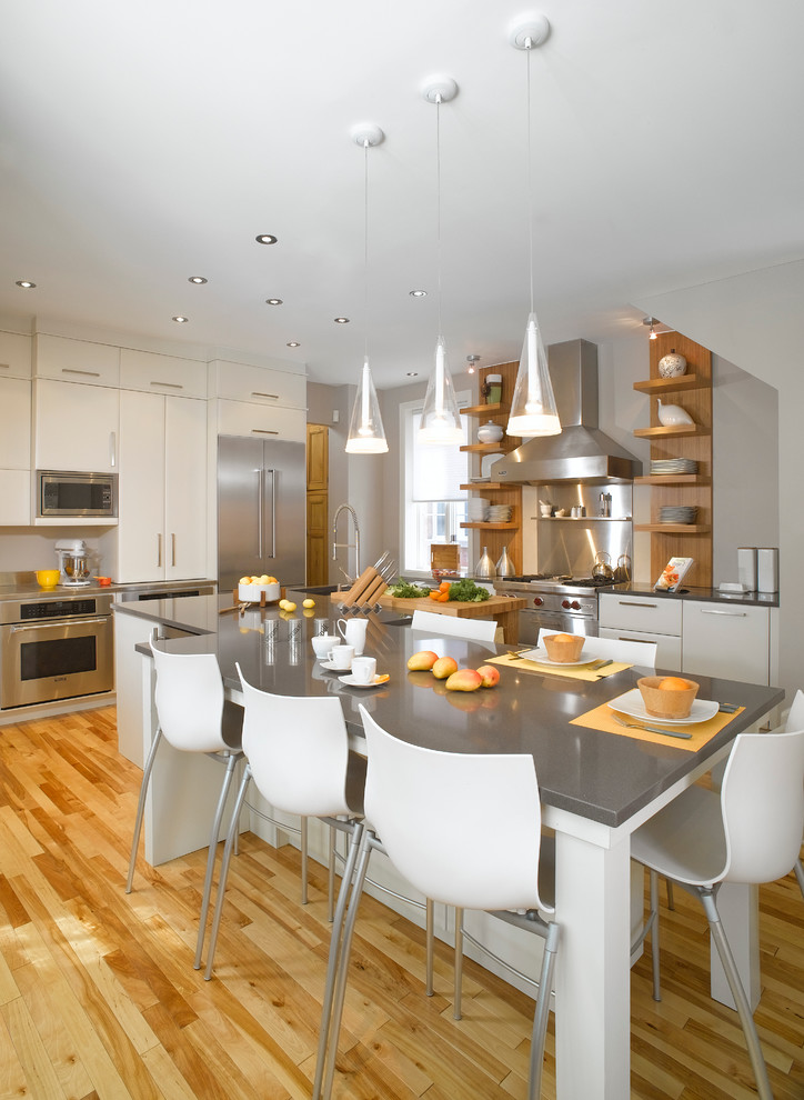 Exempel på ett stort modernt kök, med rostfria vitvaror, en undermonterad diskho, släta luckor, vita skåp, bänkskiva i kvarts, stänkskydd med metallisk yta, stänkskydd i metallkakel, ljust trägolv och en köksö
