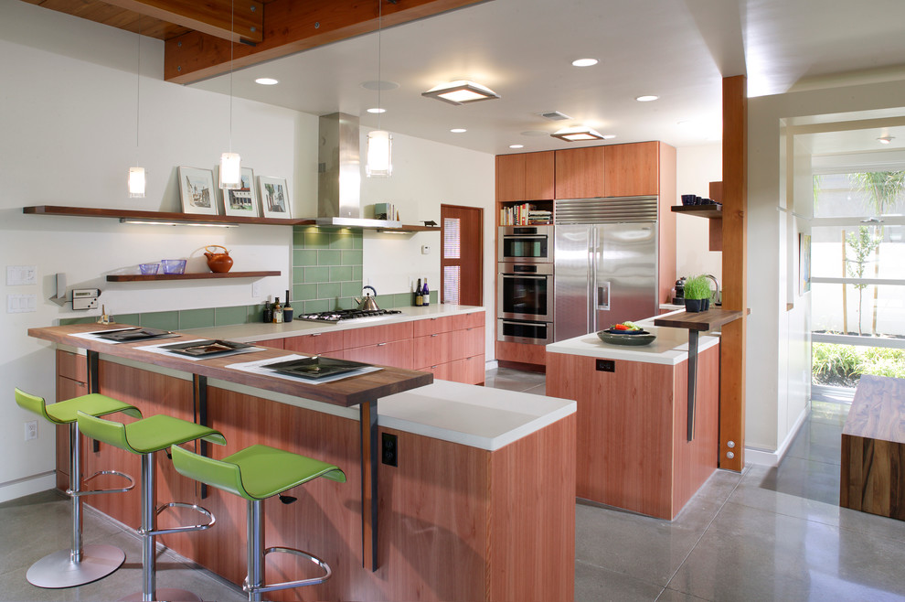 Idées déco pour une cuisine contemporaine en bois brun avec un placard à porte plane, un électroménager en acier inoxydable et une crédence verte.