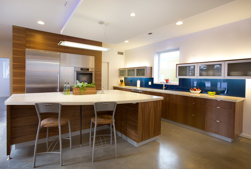 Example of a trendy concrete floor and gray floor kitchen design in Salt Lake City with flat-panel cabinets, medium tone wood cabinets, blue backsplash, glass sheet backsplash, stainless steel appliances and an island