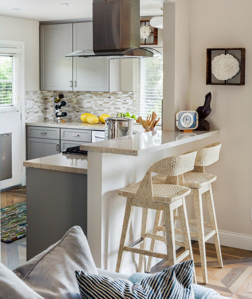 Open concept kitchen - coastal l-shaped light wood floor open concept kitchen idea in Phoenix with shaker cabinets, gray cabinets, beige backsplash, matchstick tile backsplash, stainless steel appliances and a peninsula