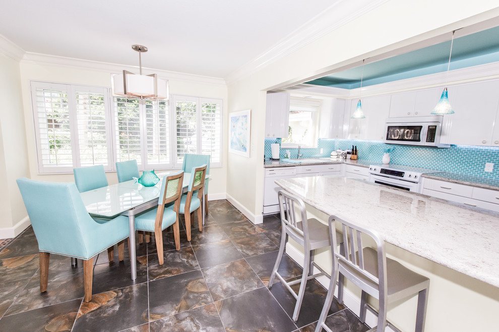 Mid-sized beach style single-wall eat-in kitchen photo in Miami with an undermount sink, flat-panel cabinets, white cabinets, granite countertops, blue backsplash, glass tile backsplash, white appliances and a peninsula