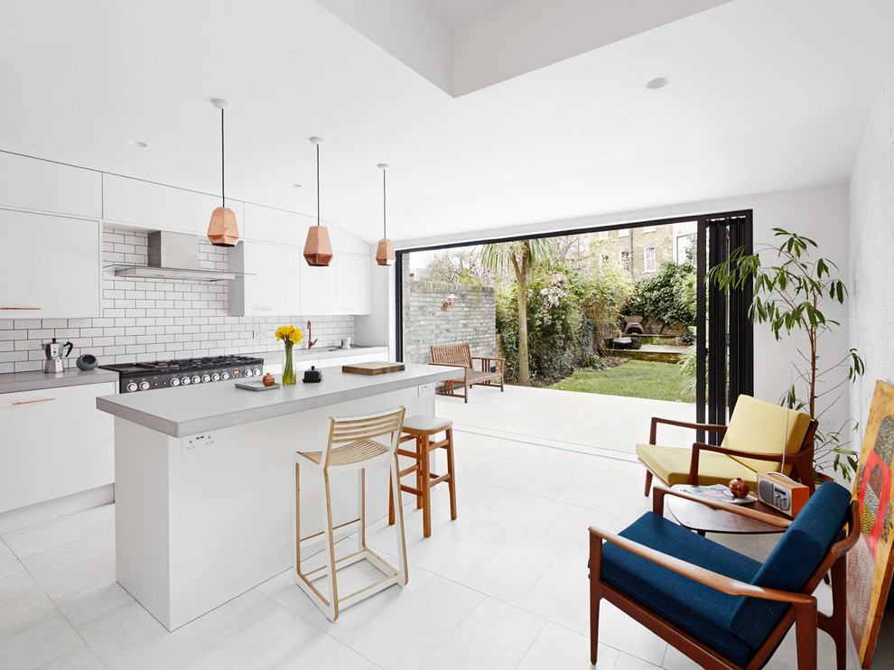 Moderne Küche mit flächenbündigen Schrankfronten, weißen Schränken, Küchenrückwand in Weiß, Rückwand aus Metrofliesen, Kücheninsel und weißem Boden in London