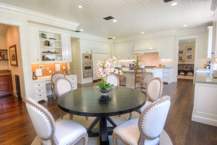 Moderne Küche mit weißen Schränken, Granit-Arbeitsplatte, Küchenrückwand in Weiß, dunklem Holzboden und zwei Kücheninseln in Orange County