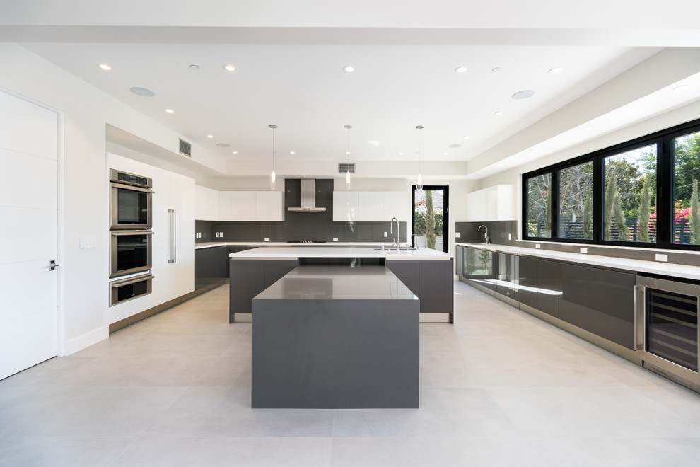 This is an example of a large contemporary u-shaped kitchen/diner in Los Angeles with a single-bowl sink, flat-panel cabinets, grey cabinets, quartz worktops, grey splashback, stone slab splashback, stainless steel appliances, porcelain flooring, an island, grey floors and white worktops.