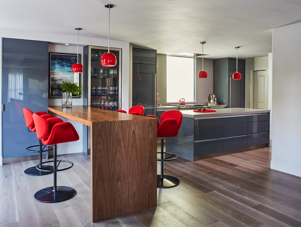 Zweizeilige Moderne Küche mit flächenbündigen Schrankfronten, grauen Schränken, dunklem Holzboden und Kücheninsel in Los Angeles