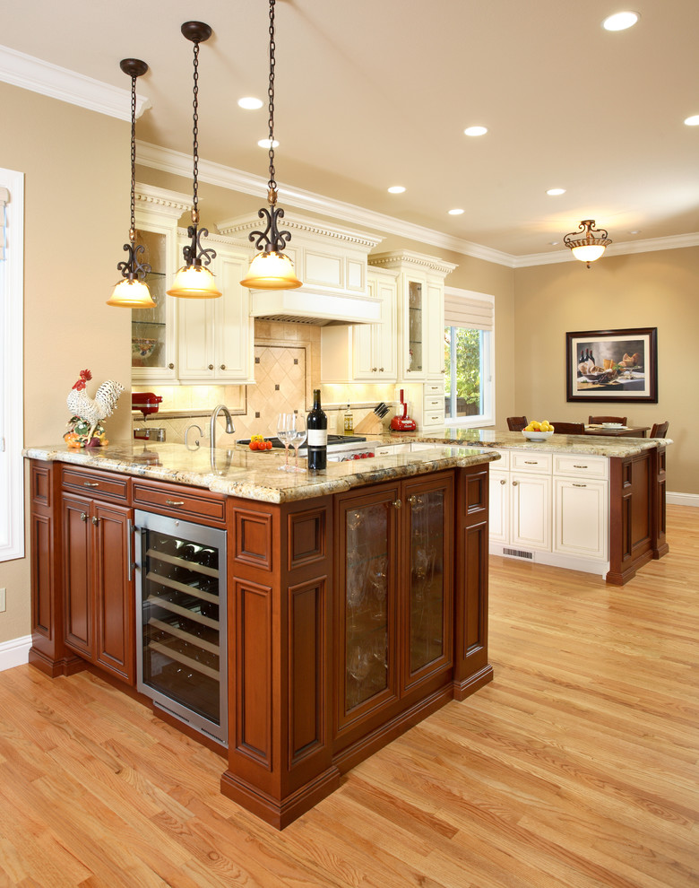 Réalisation d'une cuisine bicolore tradition en U et bois brun de taille moyenne avec un plan de travail en granite, un évier encastré, un placard avec porte à panneau encastré, une crédence beige, un électroménager en acier inoxydable, parquet clair, une péninsule et une crédence en pierre calcaire.