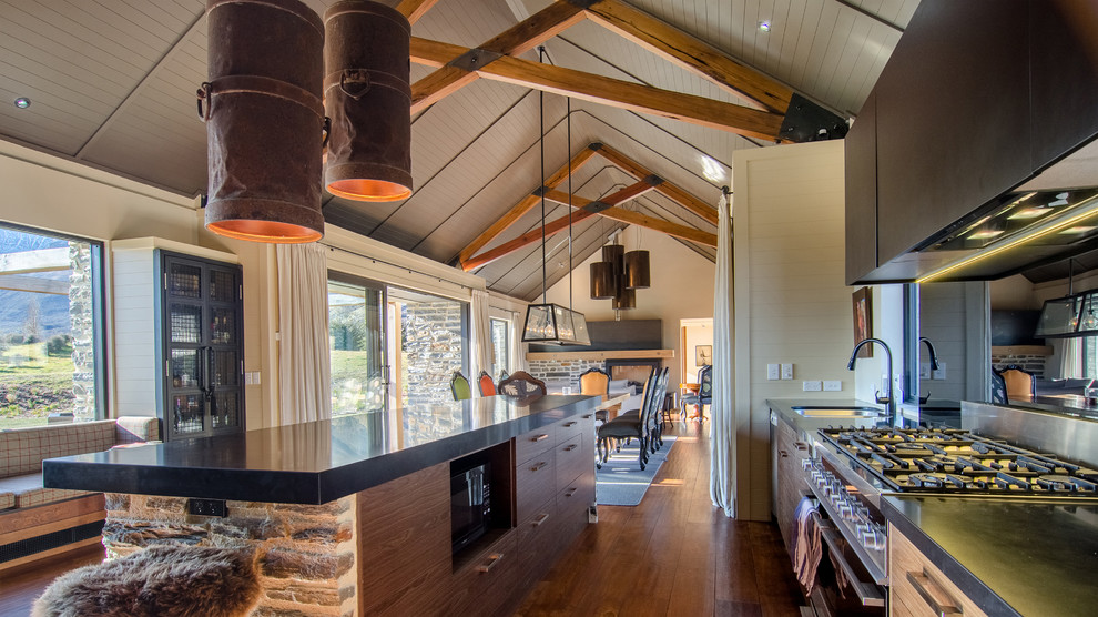Cette image montre une cuisine ouverte linéaire rustique en bois clair avec un évier encastré, un placard à porte plane, une crédence métallisée, un sol en bois brun et îlot.