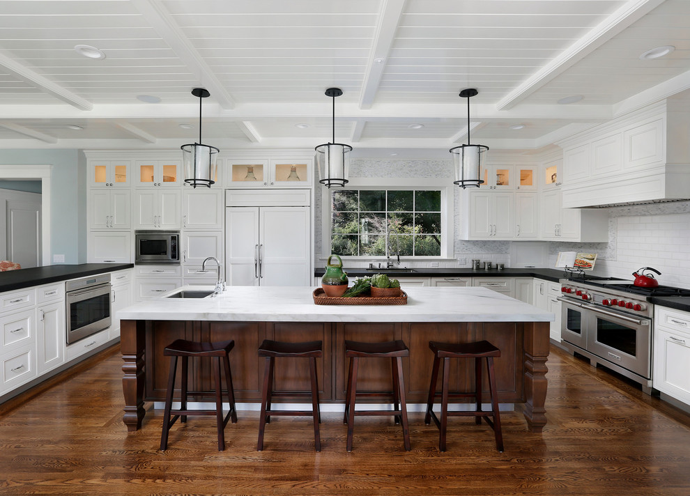 Inspiration for a large timeless u-shaped dark wood floor and brown floor enclosed kitchen remodel in San Francisco with an undermount sink, recessed-panel cabinets, white cabinets, quartz countertops, white backsplash, subway tile backsplash, paneled appliances and an island
