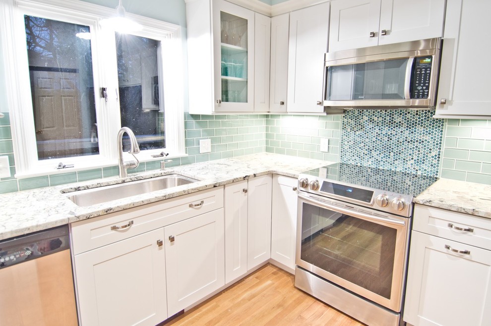 Eat-in kitchen - small transitional l-shaped light wood floor and beige floor eat-in kitchen idea in Boston with an undermount sink, shaker cabinets, white cabinets, green backsplash, subway tile backsplash, stainless steel appliances, an island and gray countertops