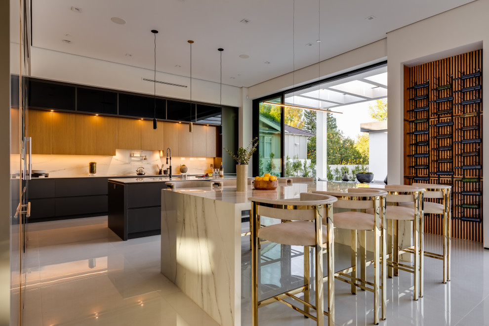 Huge trendy galley porcelain tile and white floor eat-in kitchen photo in Los Angeles with an undermount sink, flat-panel cabinets, gray cabinets, solid surface countertops, white backsplash, porcelain backsplash, black appliances, two islands and white countertops