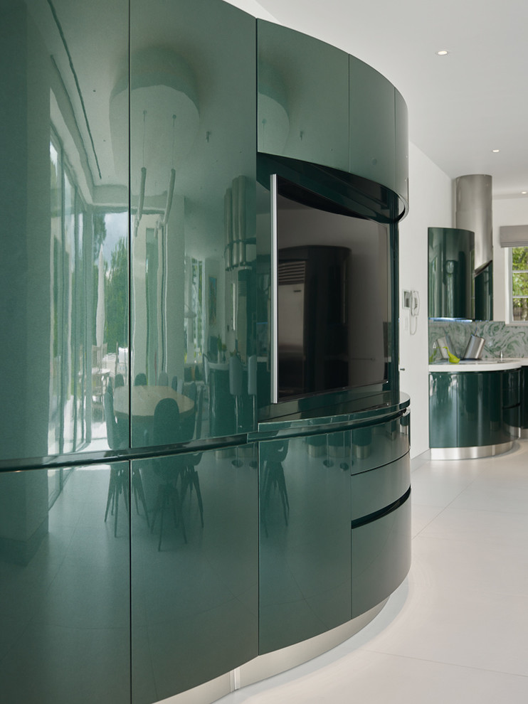 This is an example of an expansive contemporary open plan kitchen in London with an integrated sink, flat-panel cabinets, green cabinets, engineered stone countertops, green splashback, glass sheet splashback, stainless steel appliances, porcelain flooring and an island.