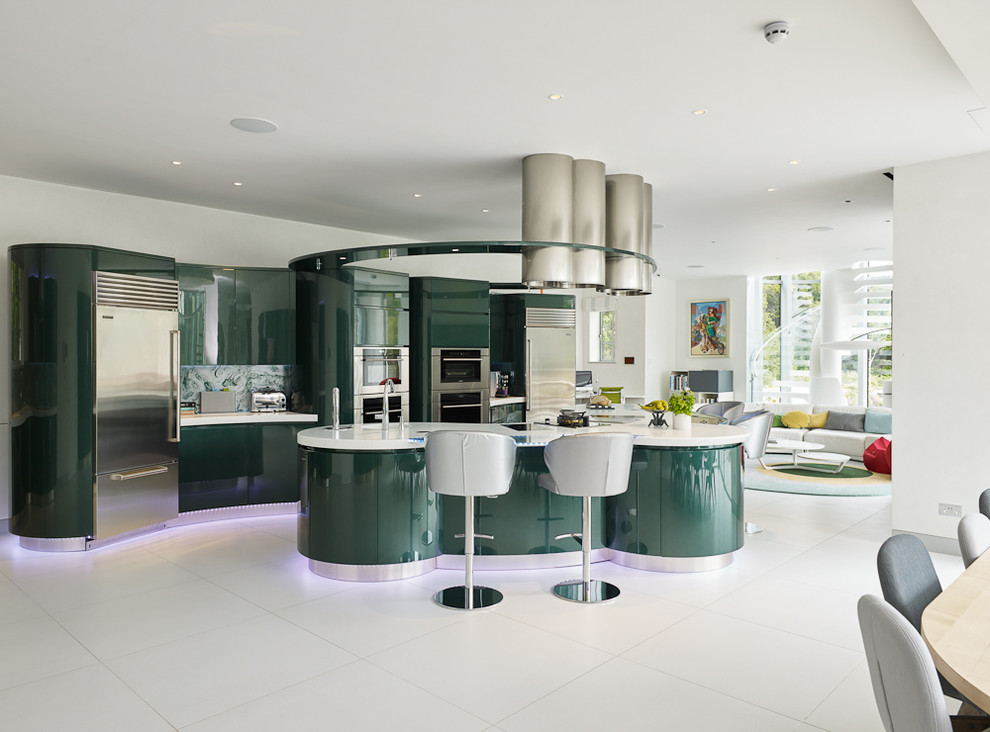 Design ideas for an expansive contemporary open plan kitchen in London with an integrated sink, flat-panel cabinets, green cabinets, engineered stone countertops, green splashback, glass sheet splashback, stainless steel appliances, porcelain flooring and an island.