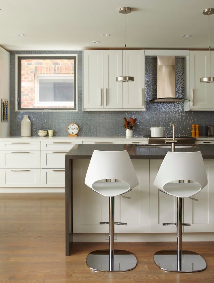 Zweizeilige Moderne Küche mit Schrankfronten im Shaker-Stil, weißen Schränken, Küchenrückwand in Metallic, Rückwand aus Mosaikfliesen, braunem Holzboden und Kücheninsel in Toronto