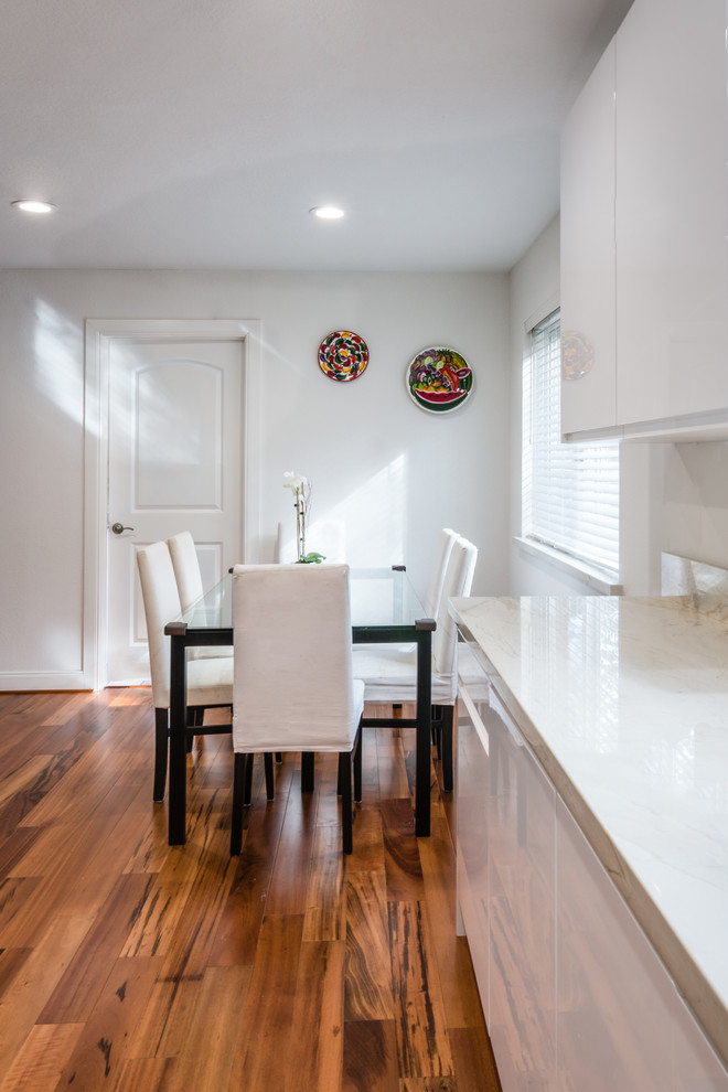 Eat-in kitchen - mid-sized contemporary u-shaped light wood floor eat-in kitchen idea in Houston with an undermount sink, flat-panel cabinets, white cabinets, quartzite countertops, beige backsplash, glass tile backsplash, stainless steel appliances and no island