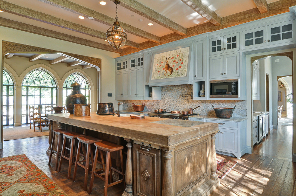 Inredning av ett klassiskt kök och matrum, med luckor med infälld panel, blå skåp, träbänkskiva, flerfärgad stänkskydd, stänkskydd i mosaik, en rustik diskho, rostfria vitvaror, mellanmörkt trägolv och brunt golv