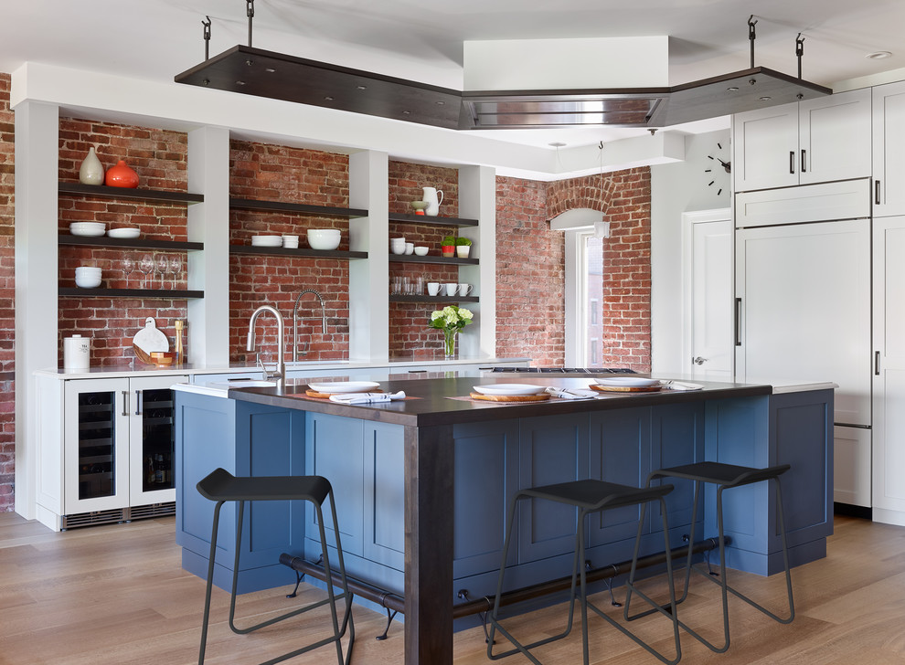 Klassische Küche mit Schrankfronten im Shaker-Stil, blauen Schränken, Küchenrückwand in Rot, Rückwand aus Backstein, hellem Holzboden, Kücheninsel, beigem Boden und brauner Arbeitsplatte in Boston