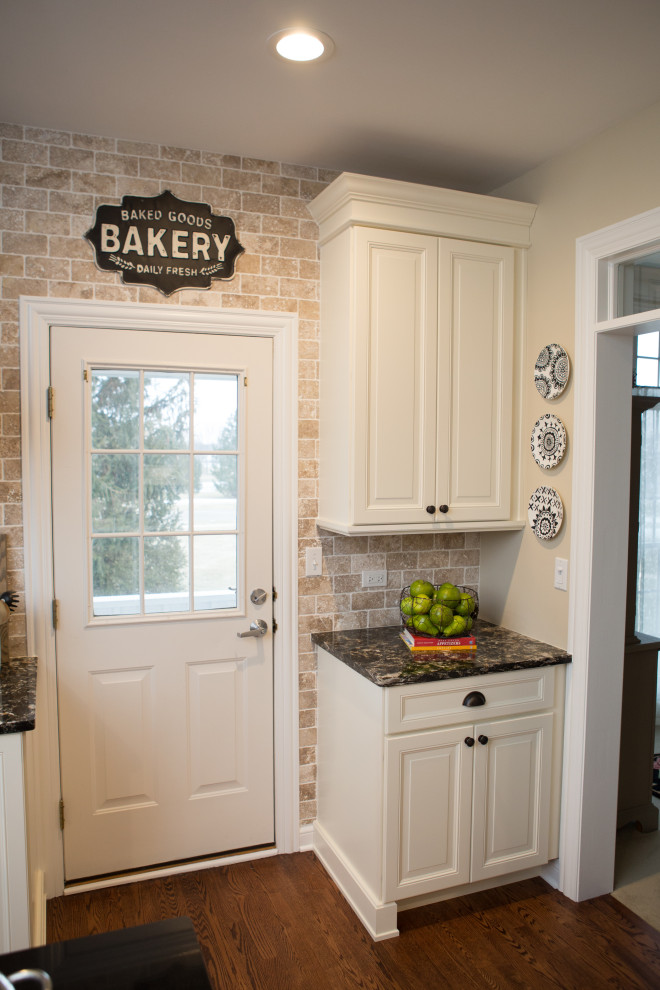 Exempel på ett mellanstort klassiskt flerfärgad flerfärgat kök, med en rustik diskho, luckor med infälld panel, skåp i ljust trä, granitbänkskiva, beige stänkskydd, stänkskydd i tegel, rostfria vitvaror, mellanmörkt trägolv, en köksö och brunt golv