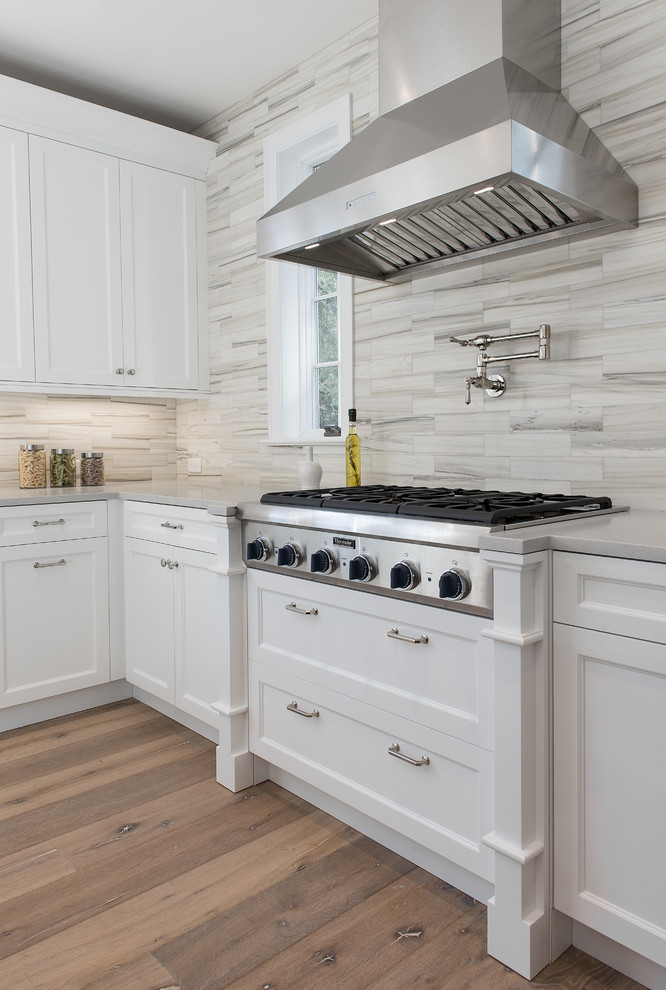 Eat-in kitchen - mid-sized traditional u-shaped light wood floor eat-in kitchen idea in New York with an undermount sink, recessed-panel cabinets, white cabinets, quartz countertops, white backsplash, subway tile backsplash, stainless steel appliances and an island