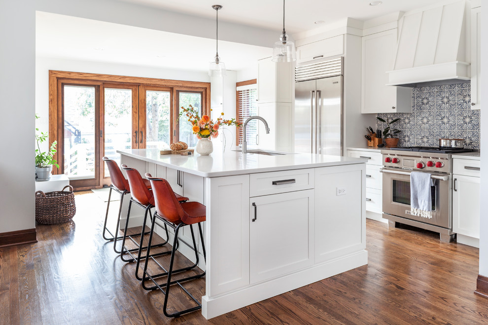 Design ideas for a traditional kitchen in Chicago with shaker cabinets, white cabinets, quartz worktops, multi-coloured splashback, stainless steel appliances, an island, brown floors, white worktops, a submerged sink and medium hardwood flooring.