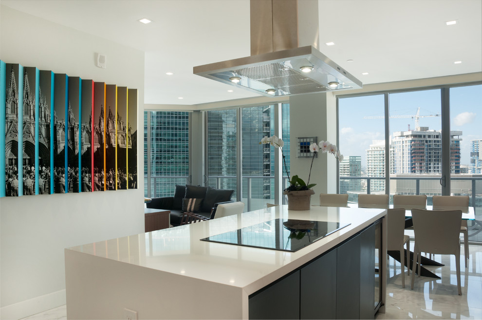Large modern l-shaped kitchen/diner in Miami with a submerged sink, glass-front cabinets, grey cabinets, quartz worktops, white splashback, slate splashback, stainless steel appliances, marble flooring, an island and white floors.