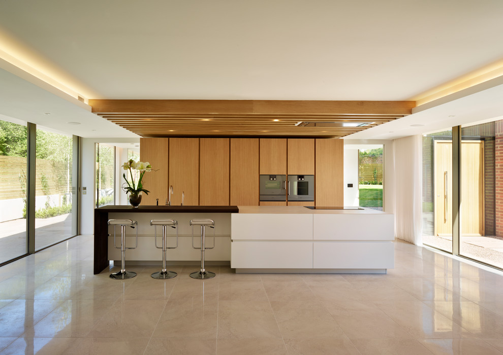 Свежая идея для дизайна: кухня в современном стиле с плоскими фасадами, светлыми деревянными фасадами и островом - отличное фото интерьера
