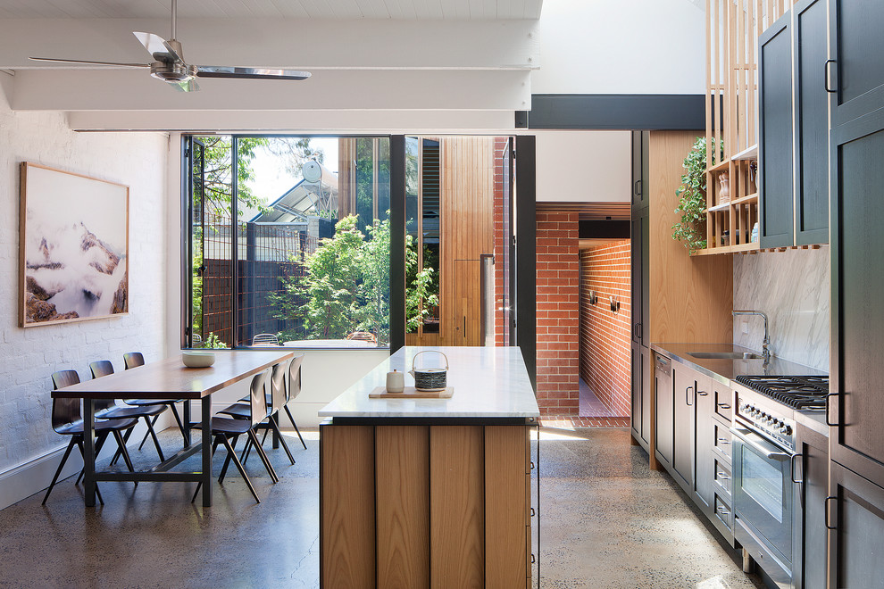 Moderne Wohnküche mit integriertem Waschbecken, Schrankfronten im Shaker-Stil, schwarzen Schränken, Edelstahl-Arbeitsplatte, Küchenrückwand in Weiß, Küchengeräten aus Edelstahl, Betonboden und Kücheninsel in Sydney