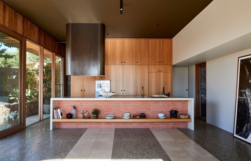 シドニーにあるインダストリアルスタイルのおしゃれなキッチン (アンダーカウンターシンク、フラットパネル扉のキャビネット、中間色木目調キャビネット、グレーの床、白いキッチンカウンター) の写真
