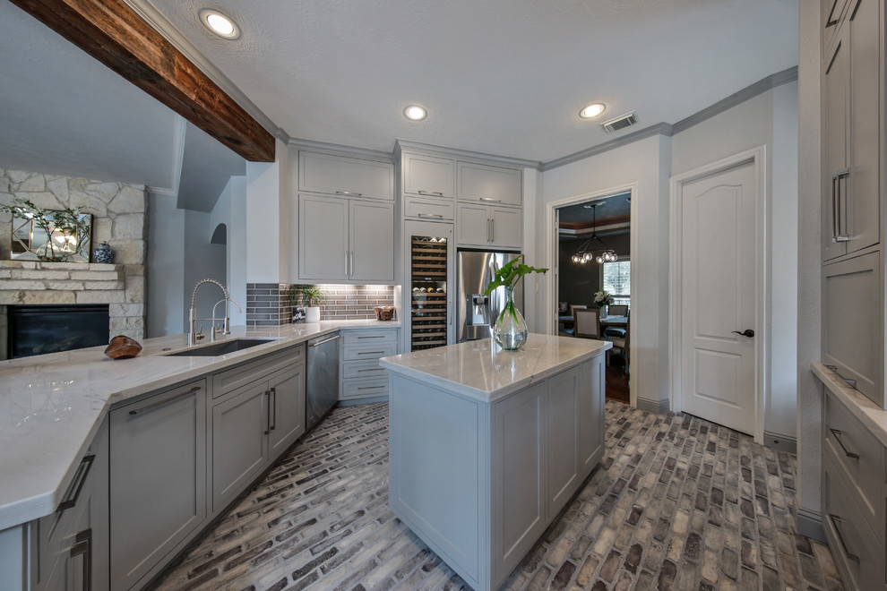 Inredning av ett klassiskt mellanstort kök, med en undermonterad diskho, luckor med infälld panel, grå skåp, marmorbänkskiva, brunt stänkskydd, stänkskydd i porslinskakel, rostfria vitvaror, tegelgolv, en köksö och brunt golv