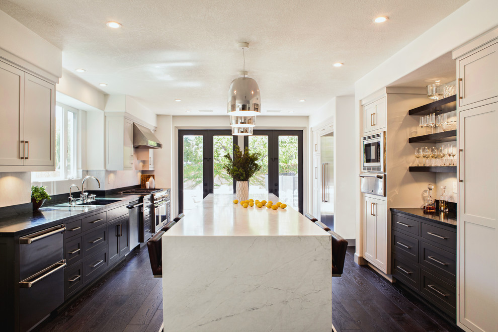 Imagen de cocina clásica renovada grande abierta con armarios estilo shaker, puertas de armario grises, salpicadero blanco, salpicadero de losas de piedra, electrodomésticos de acero inoxidable, suelo de madera oscura, una isla, fregadero bajoencimera y encimera de mármol