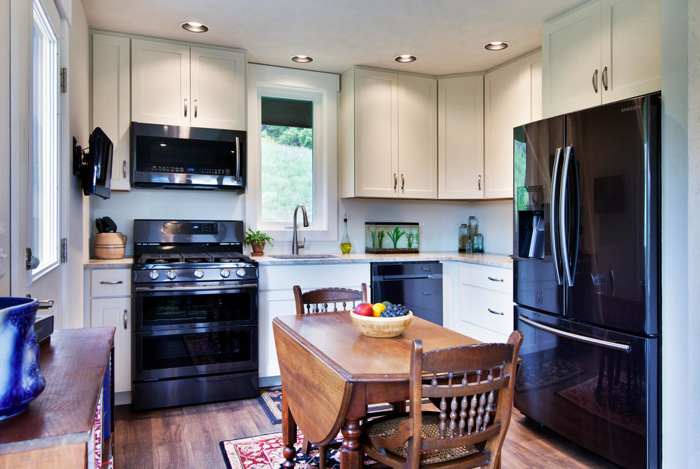 Example of a small classic l-shaped dark wood floor and brown floor kitchen design in Other with an undermount sink, shaker cabinets, beige cabinets, black appliances and no island