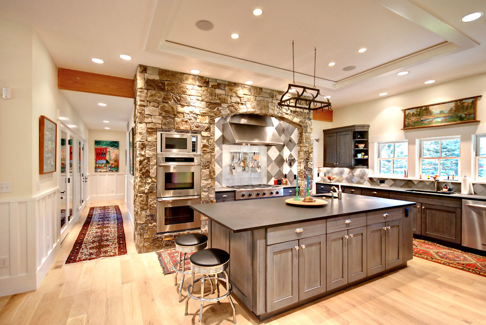 Exempel på ett stort, avskilt klassiskt l-kök, med en undermonterad diskho, bänkskiva i zink, grått stänkskydd, rostfria vitvaror, ljust trägolv, en köksö, luckor med infälld panel, grå skåp och brunt golv