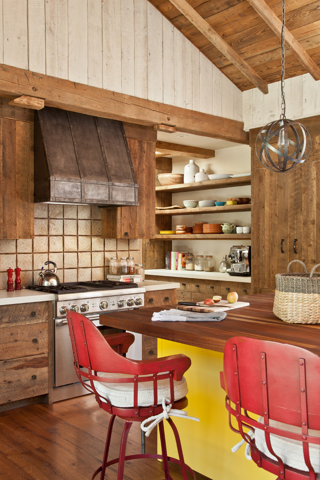 Exemple d'une cuisine montagne en bois brun avec un placard sans porte, un plan de travail en bois, une crédence beige, un électroménager en acier inoxydable, un sol en bois brun, îlot et un sol orange.