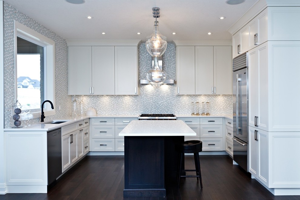 Exempel på ett klassiskt u-kök, med en undermonterad diskho, luckor med infälld panel, vita skåp, grått stänkskydd, stänkskydd i mosaik och rostfria vitvaror