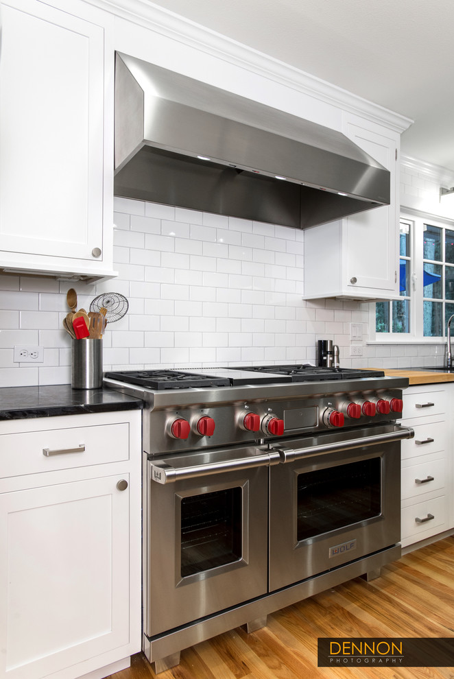 Example of a mid-sized eclectic l-shaped light wood floor open concept kitchen design in Seattle with an undermount sink, shaker cabinets, white cabinets, marble countertops, white backsplash, ceramic backsplash, stainless steel appliances and an island